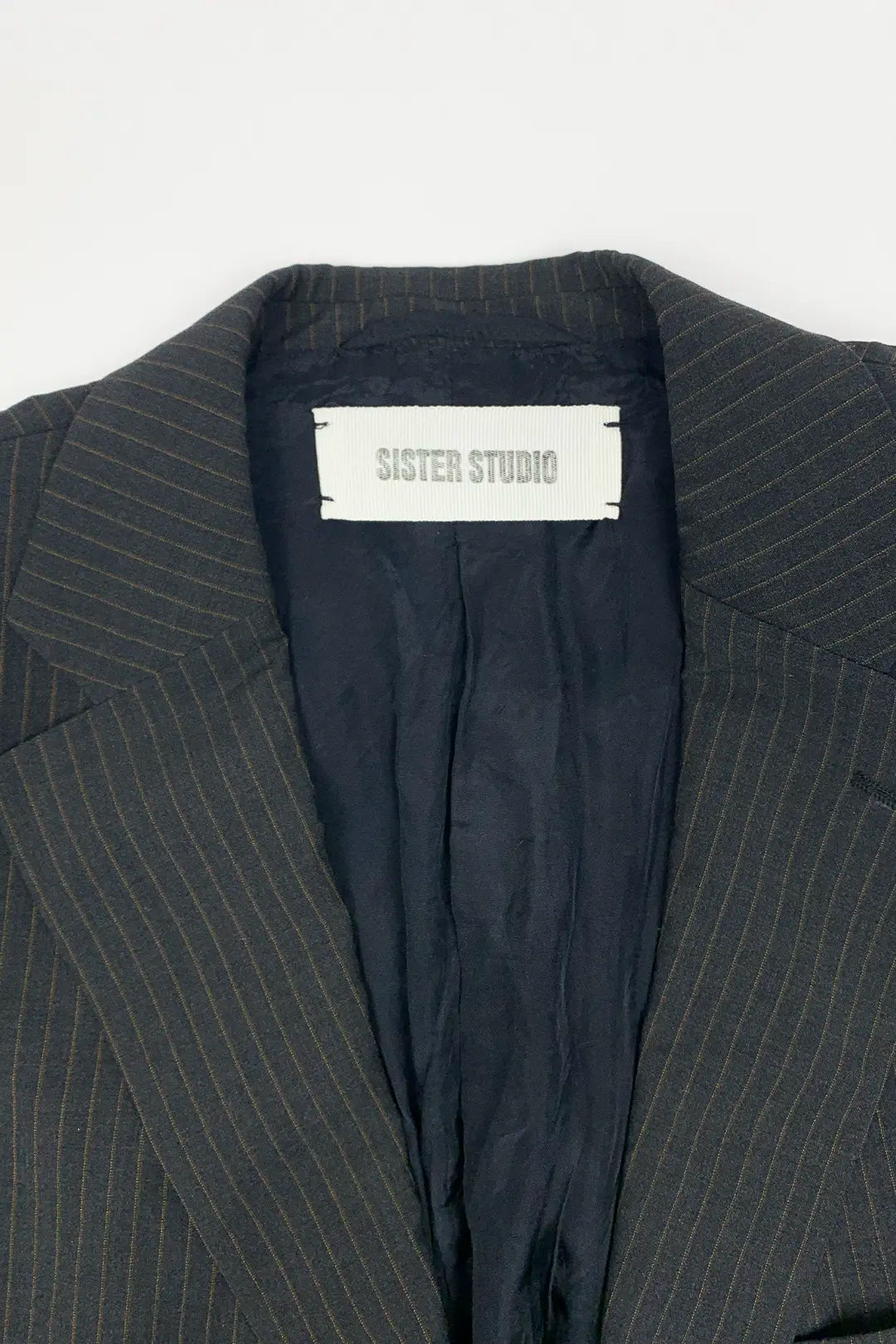brown pinstripe suit jacket with a SISTER STUDIO label on a light gray background