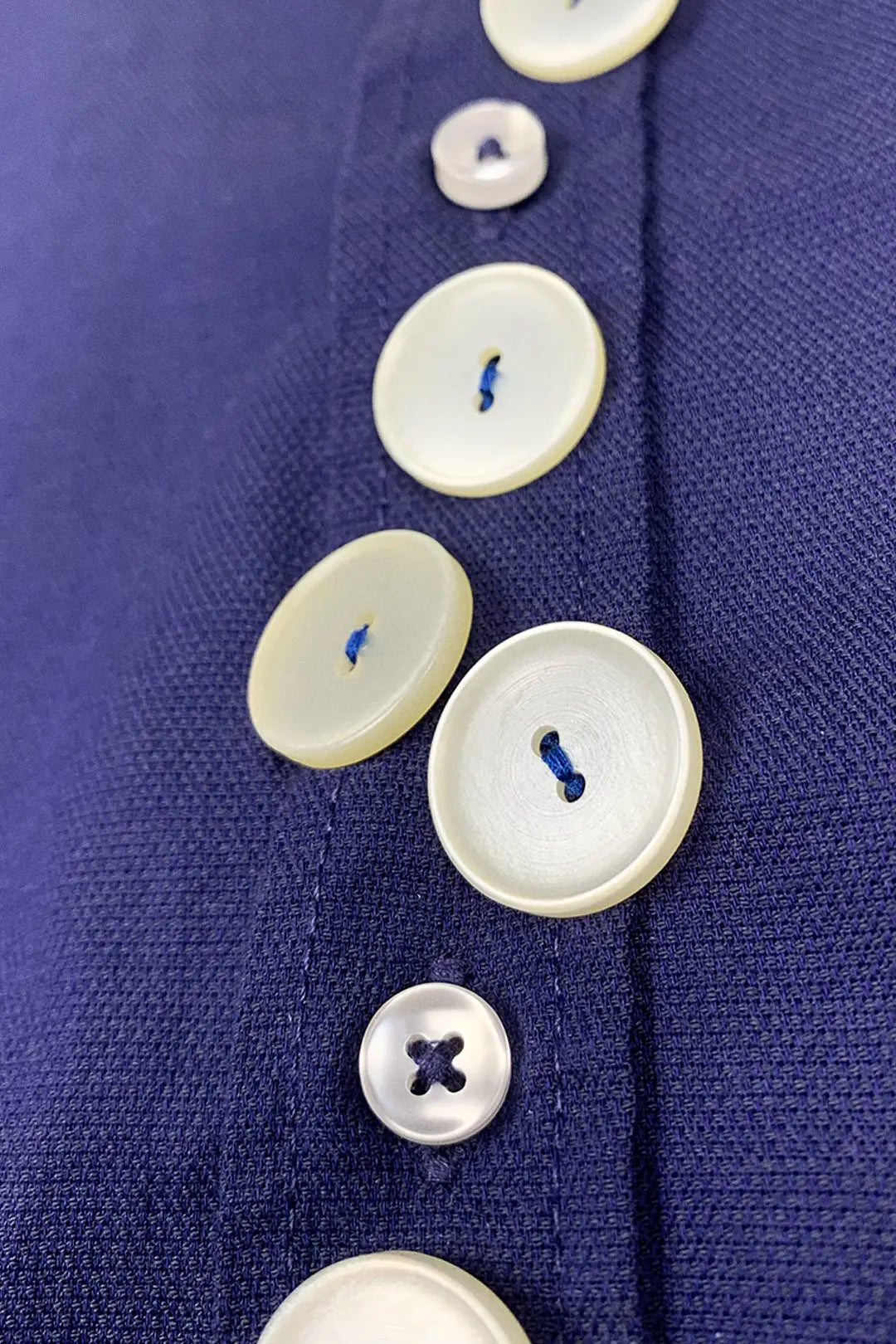detail of beige buttons on blue cotton shirt