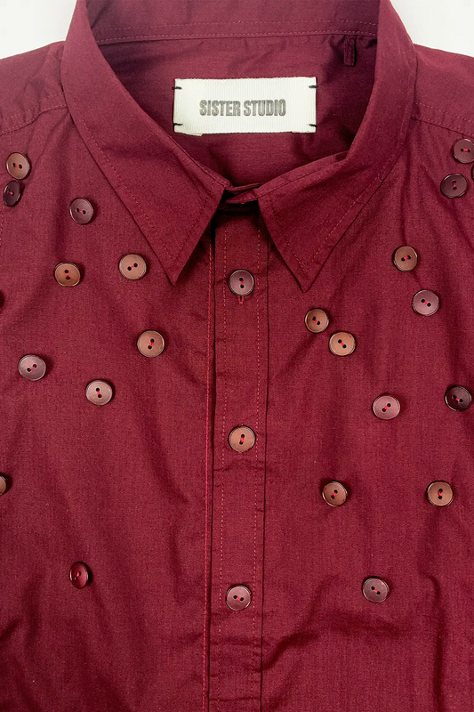 Burgundy shirt with button details and 'Sister Studio' label on a white background