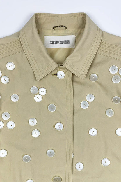 Beige jacket with button embellishments on a white background, featuring 'Sister Studio' label.
