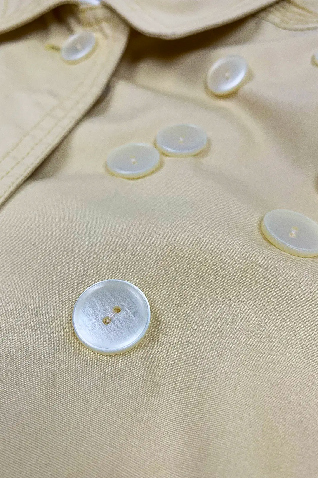 Close-up of beige fabric with buttons on a garment