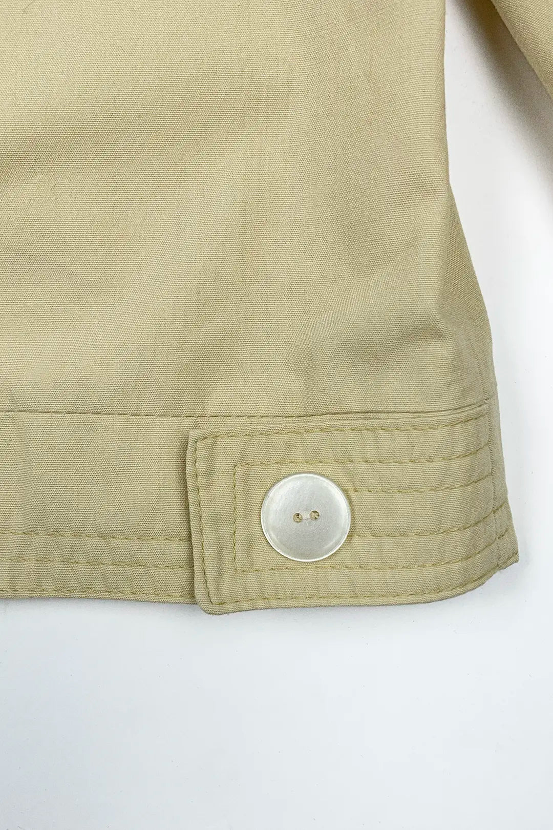 Close-up of a beige jacket with a button on a white background