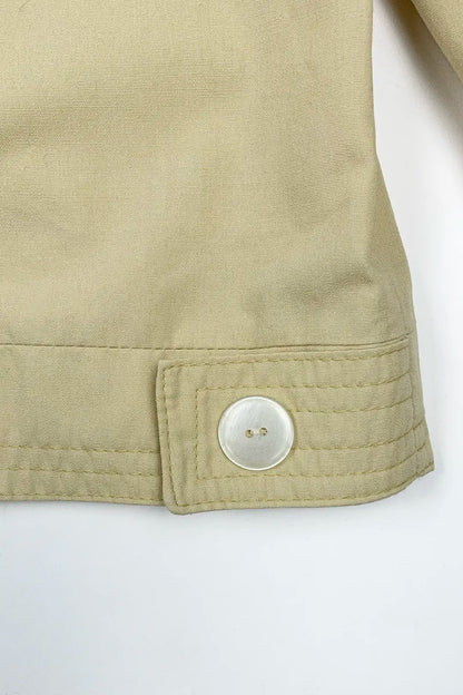 Close-up of a beige jacket with a button on a white background