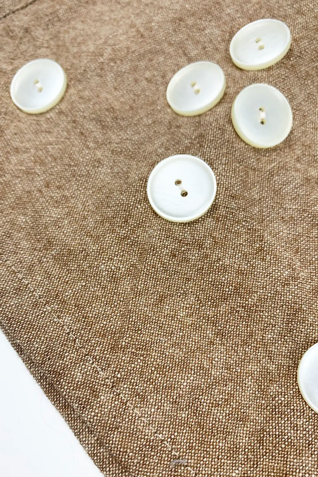 White buttons on a textured brown fabric surface