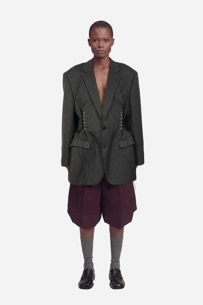 Person wearing a dark brown blazer and maroon shorts on a white background