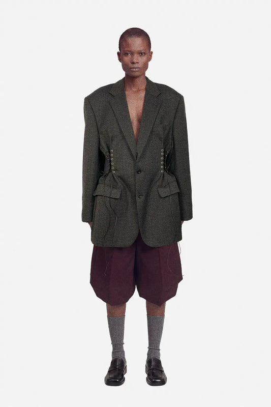 Person wearing a dark brown blazer and maroon shorts on a white background