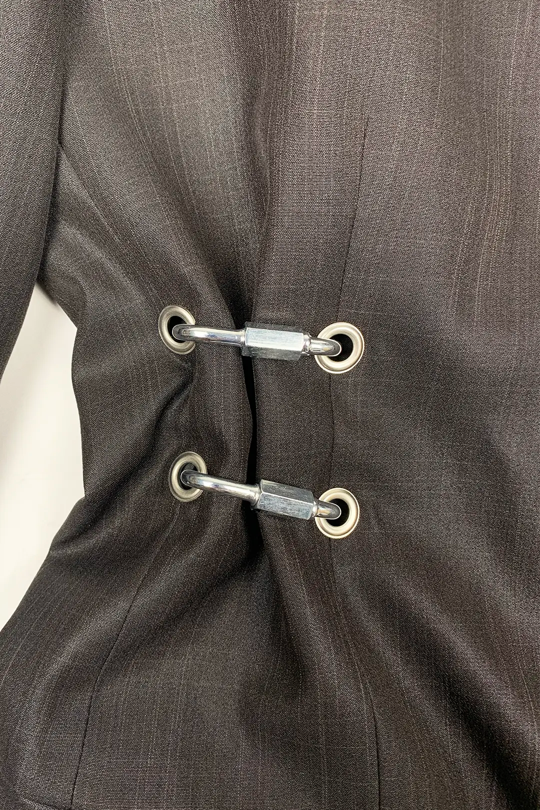 Close-up of a brown suit with metal hardware details on a white background