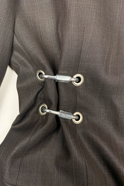 Close-up of a brown suit with metal hardware details on a white background