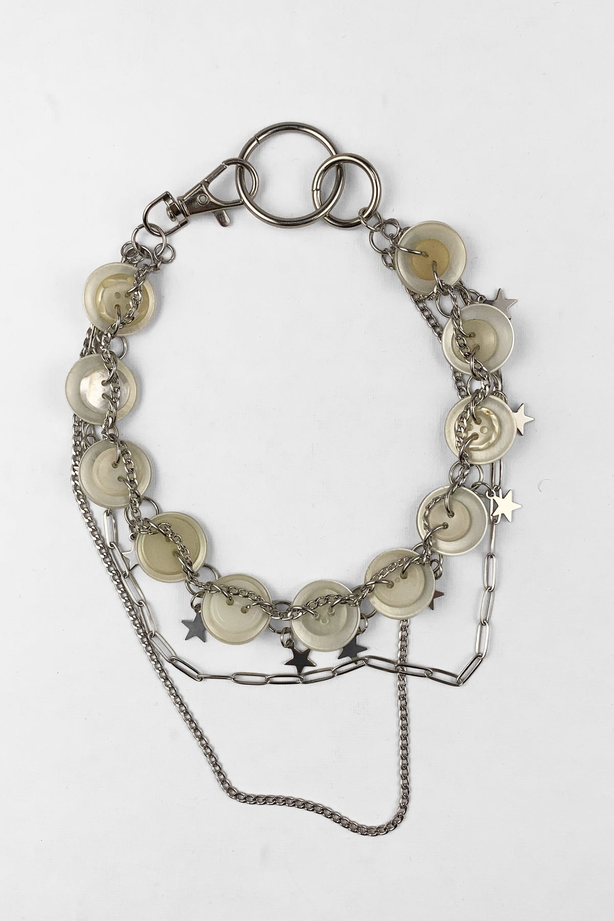A silver-toned chain bracelet featuring round cream-colored shell discs, small star charms, and a lobster clasp, displayed on a clean white background.