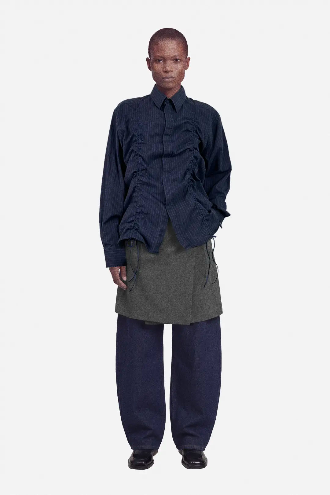 Person wearing a dark blue layered outfit with a gray skirt on a white background, ruched shirt, upcycled