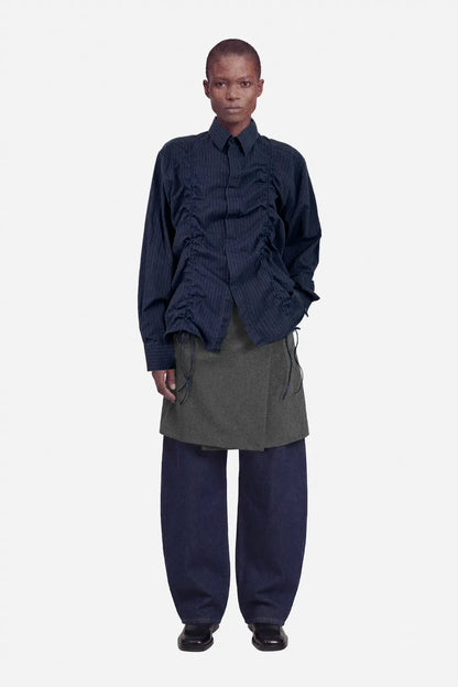 Person wearing a dark blue layered outfit with a gray skirt on a white background, ruched shirt, upcycled