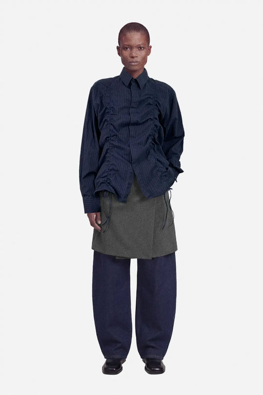 Person wearing a dark blue layered outfit with a gray skirt on a white background, ruched shirt, upcycled