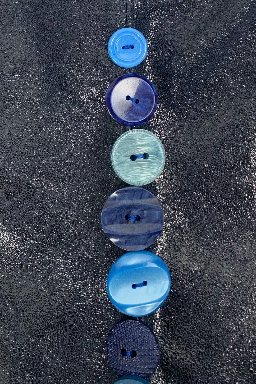 Blue buttons arranged vertically on a textured navy leather surface