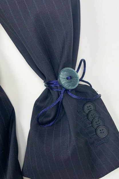 Navy pinstripe suit jacket with a decorative button and blue ribbon on a white background