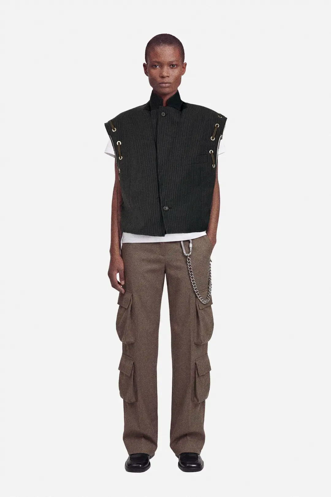 Person wearing a brown pinstripe vest with metal accents and brown cargo pants on a white background