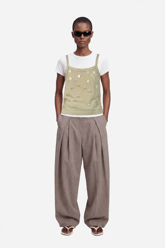 Person wearing a beige upcycled top with button details and white shirt on a white background