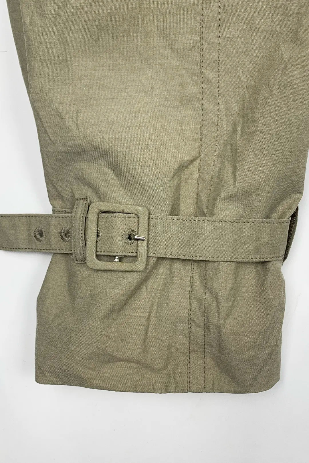 Close-up of a beige trench jacket with a belt and buckle on a white background