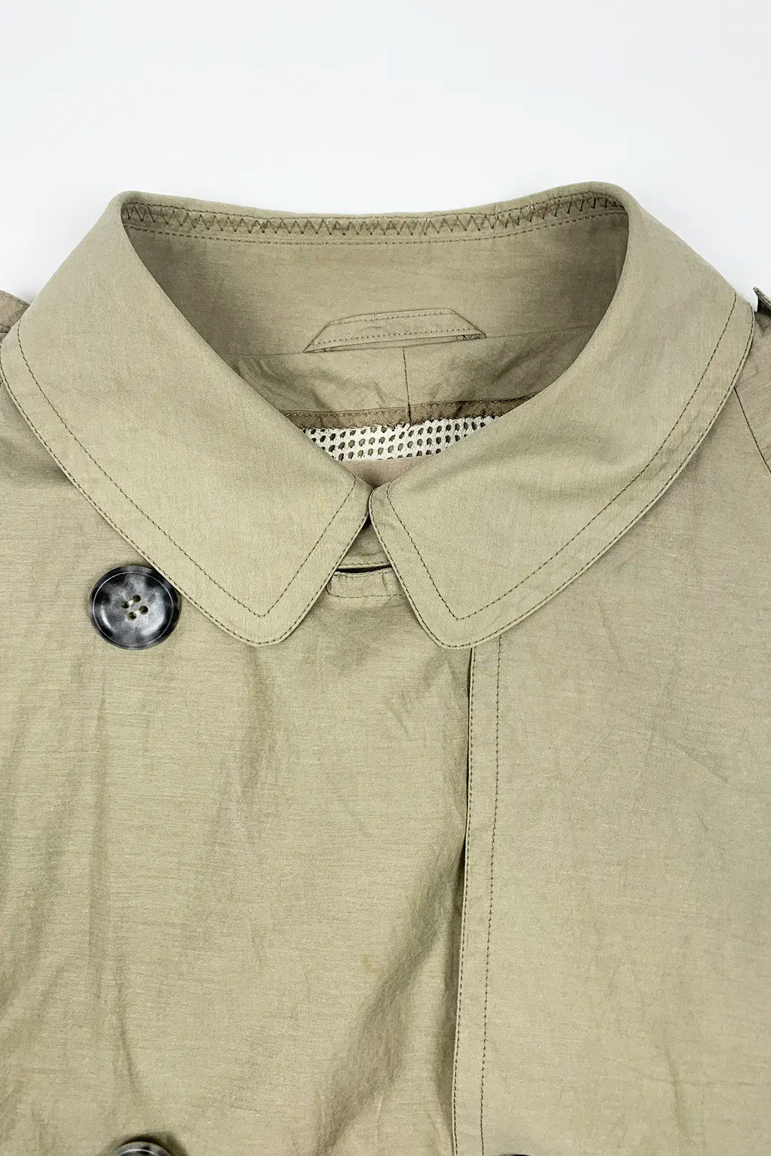Close-up of a beige  trench jacket with a collar and button on a white background