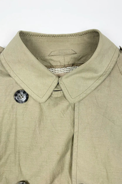 Close-up of a beige  trench jacket with a collar and button on a white background